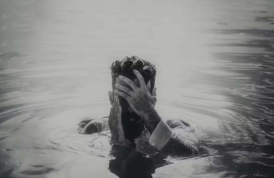 swimmer covering face in a black swimming pool
