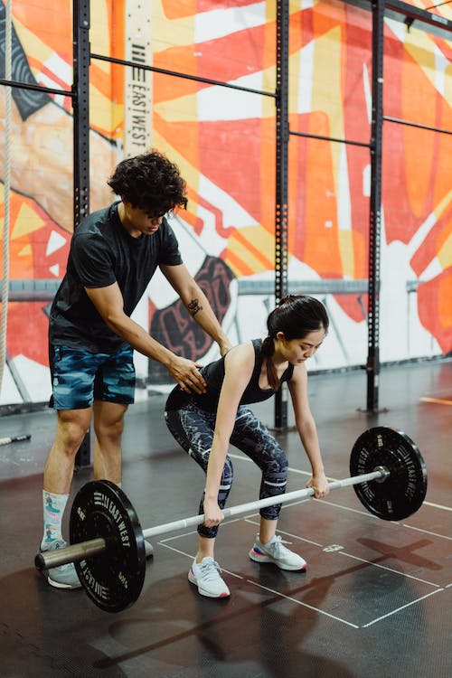 female swimmer lifting weight with a male coach